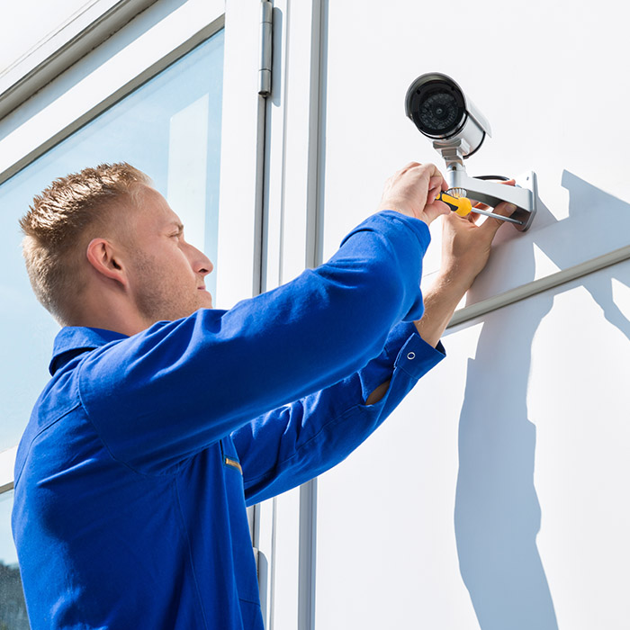 Technician Fixing Camera On Wall